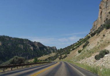 Wyoming, ABD'deki Bighorn Dağları boyunca jeolojik oluşumlar ve kayalıklar ile dolambaçlı bir yolun geniş manzaralı.