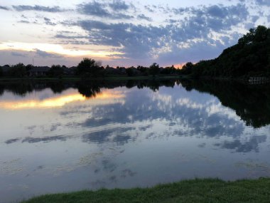 Göl kenarında güzel gün batımı, suda yansımaları ile