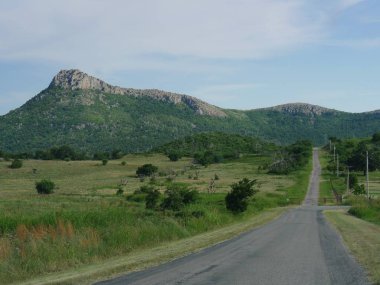 Straight road to the Wichita Mountains in the background, Oklahoma. clipart