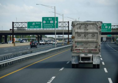 New York, Abd- Eylül 2017: New York'a yaklaşan eyaletler arası yolda yön işaretleri olan bir üst geçitten geçmek için bir damperli kamyon gidiyor.