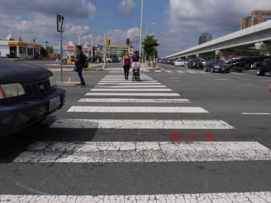 Tysons, Virginia- Eylül 2017: Bebek arabasında bebekli bir çift Tysons, Virginia'da yaya geçidinden geçiyor.