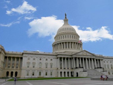 Washington, D.C. ABD- Eylül 2017: Columbia Bölgesi'nin Başkenti Washington'da beton bir bankta oturan üç kişinin bulunduğu ABD Kongre Binası'nın görünümü.