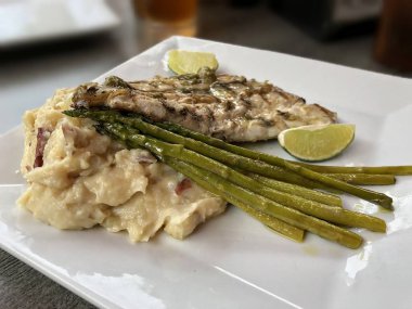 Beyaz bir tabakta kuşkonmaz ve patates salatası ile ızgara sarı snapper Orta yakın