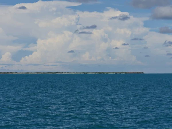 Small island in the Florida Keys, Florida in the far distance, with gorgeous clouds in the skies.