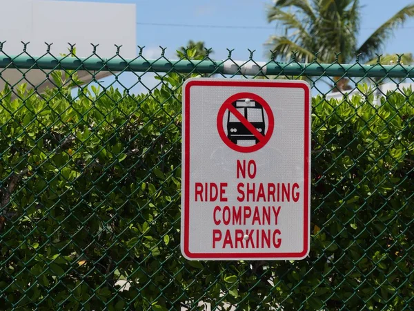 No Ride Sharing sign hanging from a cyclone wire fence