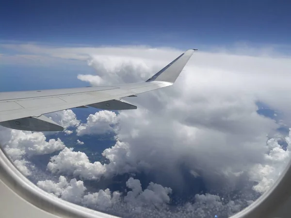 Storm clouds seen from an airplane window, with an airplane wing in view.