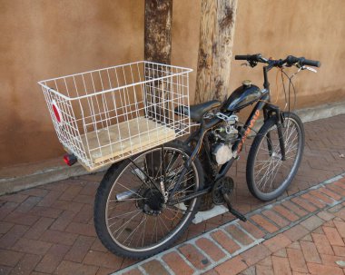 Kaldırıma park etmiş benzin deposu ve sepeti olan bir bisiklet.