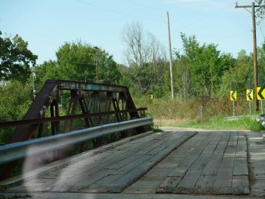 Arka yolunda paslı parmaklıkları olan eski ahşap bir köprü. 
