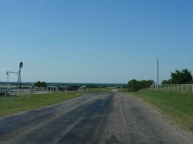 Asphalt road going up and down the hills by farmlands in Oklahoma clipart