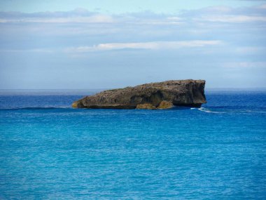 Tropikal bir plajın mavi sularında güzel bir kaya oluşumunun ortalarında. 