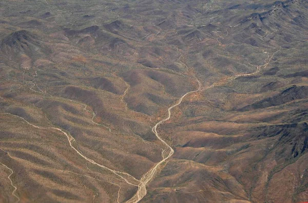 飛行機の窓から見える乾燥した山々の周りを歩き回る道路でトップからネバダ州のデザートの眺め — ストック写真