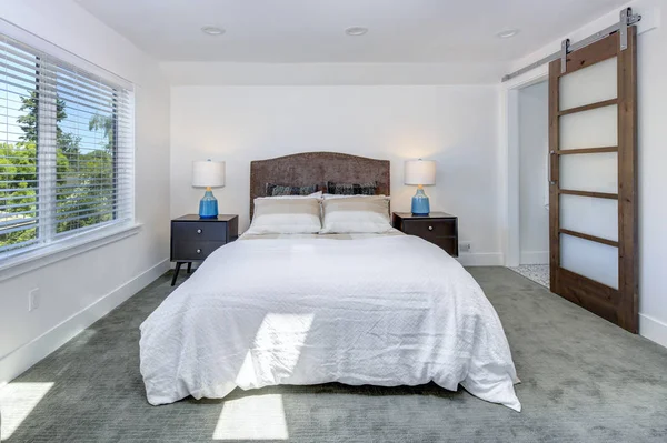 惊人的白色卧室设计与特大床旁边的滑动谷仓门 导致主浴室 — 图库照片
