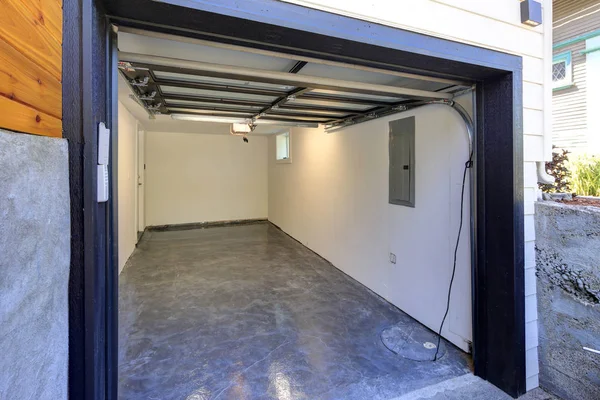 Empty garage interior with open door in renovated two story house.