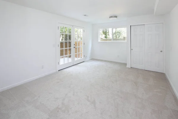 White empty room interior with glass doors to back deck.