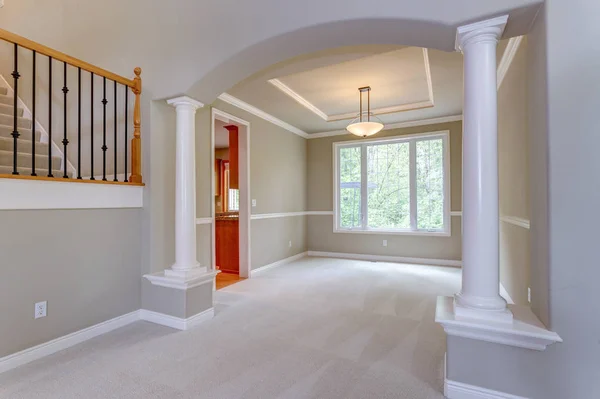Elegant arched entryway to empty dining room accented with white columns.
