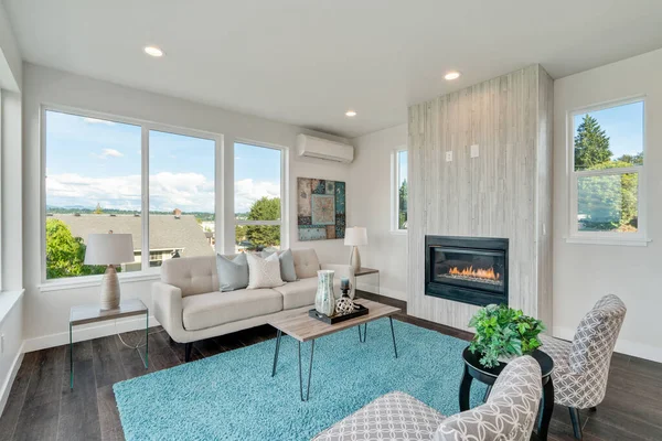 Contemporary styled living room is completed with a stone fireplace and two armless accent chairs on a turquoise fluffy rug.
