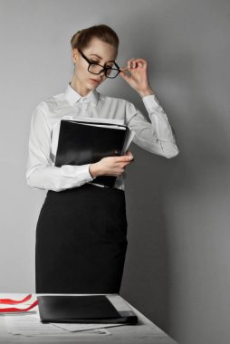 ofis çalışanı bir dizüstü gömlekli. Office beyaz duvarlı. Tablo kağıt ve klasör Gözlüklü kız.