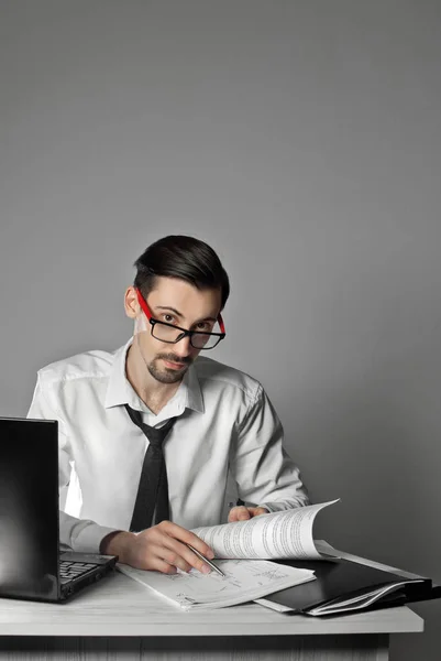 office worker in a laptop shirt. office with white walls. man in glasses on the table paper and folder.