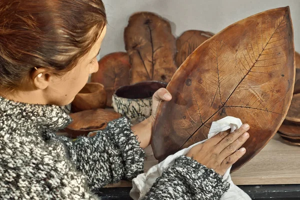 The girl paints pottery. Handmade products on the table at home workshop. Ceramic products with drawings and patterns.