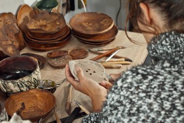 Kız kil yemekleri araçları ile açmaktadır. El yapımı ürünleri ev atölye masada. Çizimler ve desenler ile seramik ürünler.