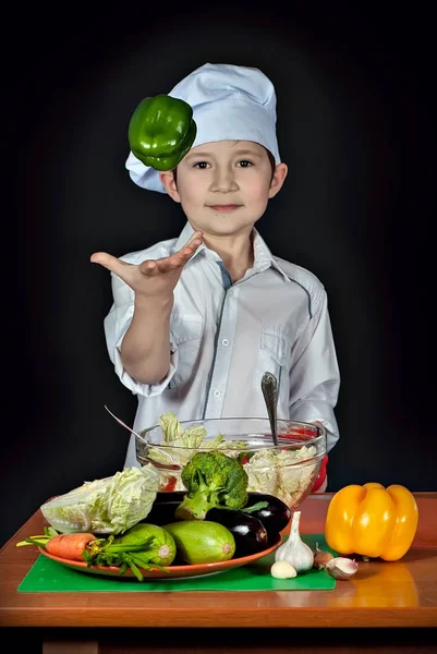 요리사 의상에서 부엌에서 샐러드를 어린이 식품을 준비합니다 소년에 후추를 던졌습니다 — 스톡 사진