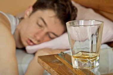 Boş bardak viski ön planda için. Sarhoş adam içinde belgili tanımlık geçmiş. Netlik camına.