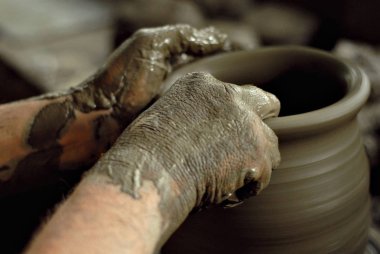 Adam bir toprak kupa süs açmaktadır. Home atölye masada el yapımı ürünler. 