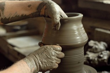 Adam bir toprak kupa süs açmaktadır. El yapımı ürünleri ev atölye masada. Çizimler ve desenler ile seramik ürünler.