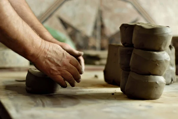 The man carves an ornament on an earthenware bowl. Handmade products on the table at home workshop.