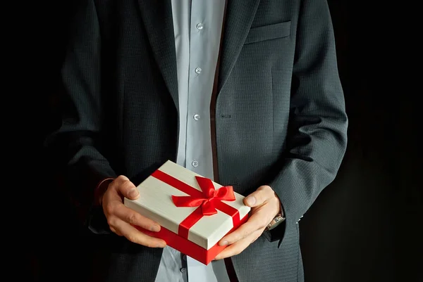 Ένας Άνθρωπος Ένα Κοστούμι Κατέχει Ένα Κουτί Δώρου Στα Χέρια — Φωτογραφία Αρχείου