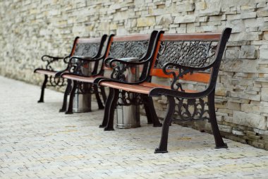 Beton duvarın yakınında bir parkta eski bir tahta tezgah.