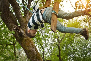 Çocuklar parkta salıncakta salıncakta. İplerden ve tahtalardan ev yapımı salıncakta adamlar. Hareketin sanatsal bir etkisi olarak ışık bulanıklığı.