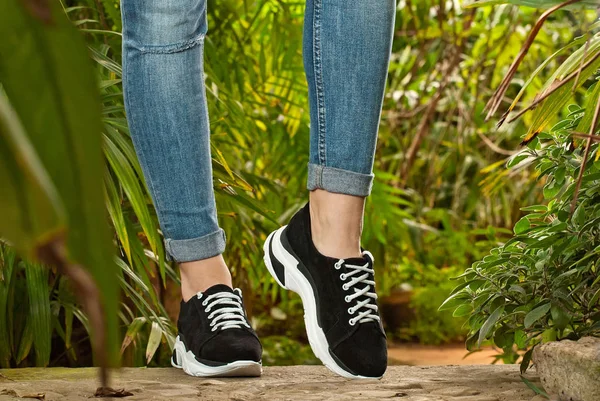 Pernas Femininas Perto Tênis Esportivos Asfalto Contra Plantas Verdes Sapatos — Fotografia de Stock