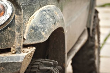 Tekerlekler, ışıklar ve tamponlar bataklıkta bağlı. Cipin kirli parçaları. Yakın plan..