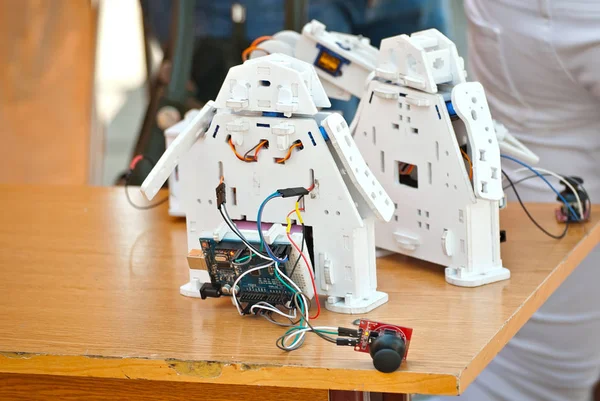 Robotics is made by children at a scientific exhibition. Multi-colored wires and microcircuits are made of plywood, designer and spare parts. Radio controlled devices.