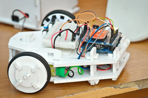 Robotics is made by children at a scientific exhibition. Multi-colored wires and microcircuits are made of plywood, designer and spare parts. Radio controlled devices.