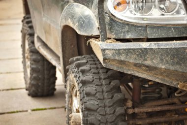 Tekerlekler, ışıklar ve tamponlar bataklığa bağlı. Bir kamyonun kirli parçaları yakın.