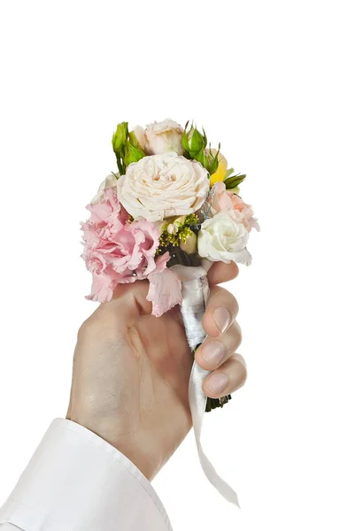 Bouquet of flowers in a man\'s hand. Little wedding bouquet on a white background. A man in a white shirt gives flowers.