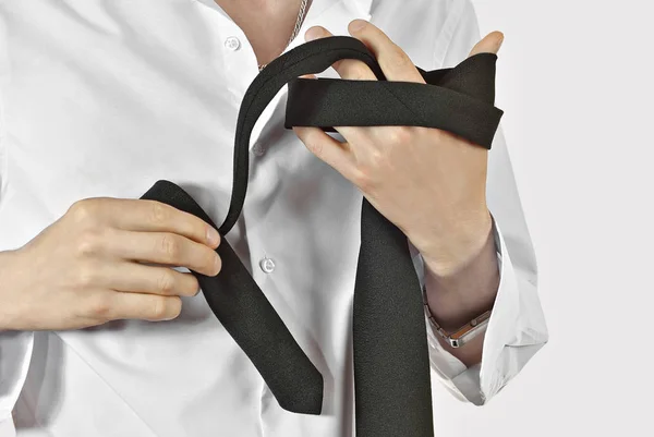男はネクタイを結んだ 結婚式の日の準備 男はネクタイに結び目をつけるのを習っている 白いシャツに黒のネクタイ クローズアップは 白い背景に分離されています — ストック写真