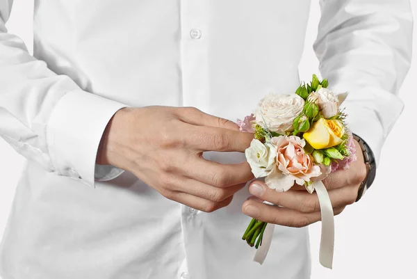 Bouquet of flowers in a man\'s hand. Little wedding bouquet on a white background. A man in a white shirt gives flowers.