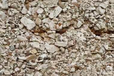 Çakıl lı beton duvar. Evin gri temeli. Duvardaki pas parçaları.