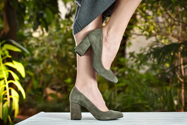 女性の脚のための緑のスエードの靴 その少女は靴を履いて歩く 熱帯植物アレンジャーの背景に古典的な靴 — ストック写真