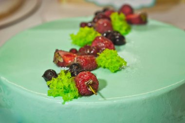 Bir vitrinde doldurulmuş yeşil ile Yuvarlak pasta. Bir pasta üzerinde Çilek.