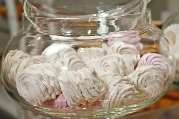 Multicolored sweets in the shop window. Many cakes on a glass shelf in a jar.