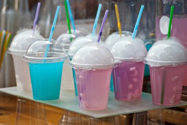 Çok renkli meyveli içecekler. Festivalde plastik bardaklarda alkolsüz içkiler. Meyve suyu ve sebzeli kokteyl. Beyaz duman kokteyllerle buharlanıyor..