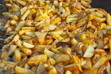 Büyük bir tavada patates kızartın. Festivalde lezzetli yemekler. Metal bir tepside masada birçok patates.