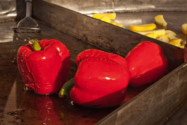 Vegetables fry on a large frying pan on fire. Cooking at the festival. Large red peppers grilled.