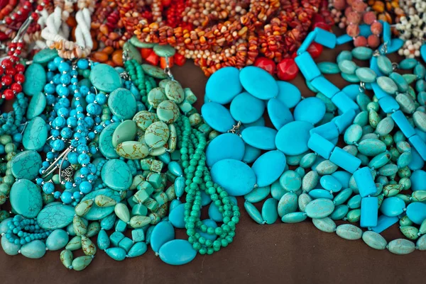 Necklace of colorful stones on the table. Many different jewelry and beads made of natural precious minerals. Turquoise jewelry is on sale at the fair.