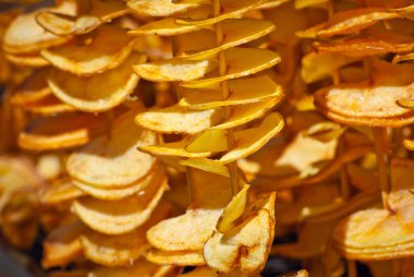 Bir sopanın üzerinde patates cipsi. Doğal cipsler kızartılır ve fuarda satılır. Yağlı sokak gıda.