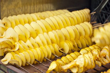 Bir sopanın üzerinde patates cipsi. Doğal cipsler kızartılır ve fuarda satılır. Yağlı sokak gıda.